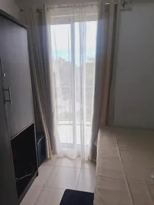 a room with a large window with a couch and a television at Flat NAIA Manila Chateau Elysee pool view in Manila