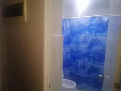 a bathroom with a toilet with a blue shower curtain at Kassel Dorz Hostel in Manila