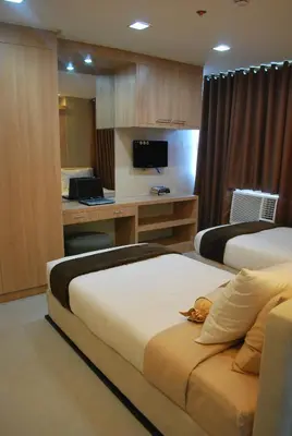 a hotel room with two beds and a desk at BSA Twin Towers in Manila