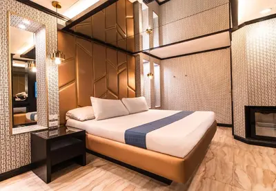 a bedroom with a bed with a mirror and a fireplace at Hotel Ava Gil Puyat in Manila
