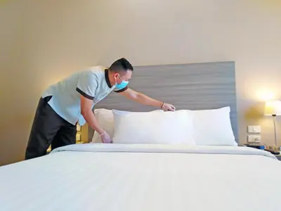 a man putting pillows on a bed in a hotel room at One Pacific Place Serviced Residences in Manila