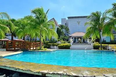 a large swimming pool with palm trees and a building at Thunderbird Resorts - Rizal in Binangonan
