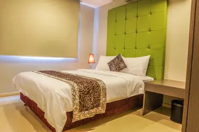 a bedroom with a bed with a green headboard at The Exchange Regency Residence Hotel Managed by HII in Manila
