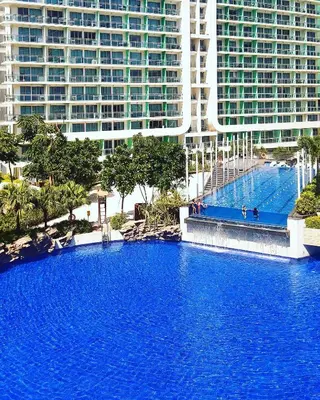 a large swimming pool in front of tall buildings at Adam'sCrib Apartment 2BR by Azure Residences Near Manila International Airport in Manila
