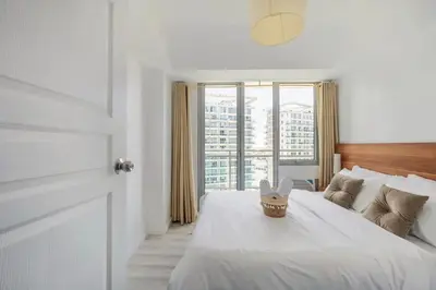 a bedroom with a white bed and a large window at Adam'sCrib Apartment 2BR by Azure Residences Near Manila International Airport in Manila