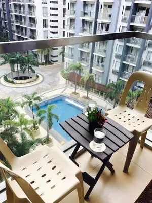 a balcony with a table and chairs and a swimming pool at Resorts World Condo in Manila
