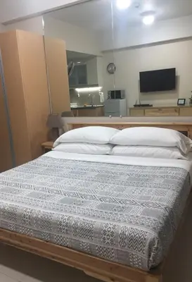 a large bed in a room with a television at 101 Newport Boulevard C1 in Manila