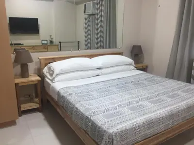 a bedroom with a large bed with a television on a table at 101 Newport Boulevard C1 in Manila