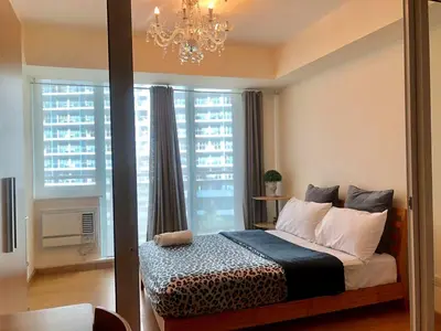 a bedroom with a bed with a chandelier and a window at Azure C6 Balcony Wifi near Mall Airport MULTIPL UNITS in Manila