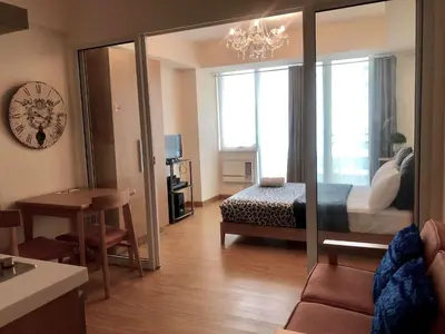 a room with a bedroom with a bed and a clock at Azure C6 Balcony Wifi near Mall Airport MULTIPL UNITS in Manila