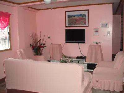 a living room with pink walls and white chairs at JCP Room Rentals in Manila