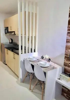 a white kitchen with a table and two chairs at EV Place in Manila