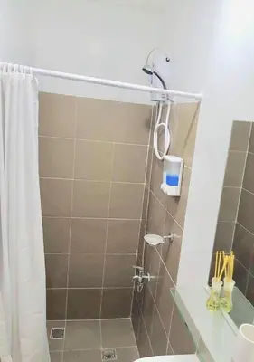 a bathroom with a shower with a toilet and a sink at EV Place in Manila