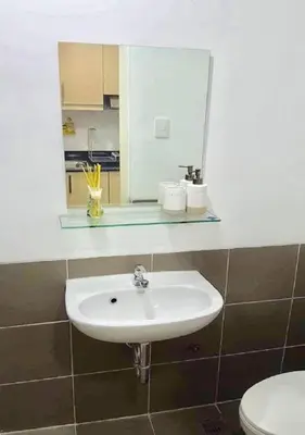 a bathroom with a sink and a mirror and a toilet at EV Place in Manila