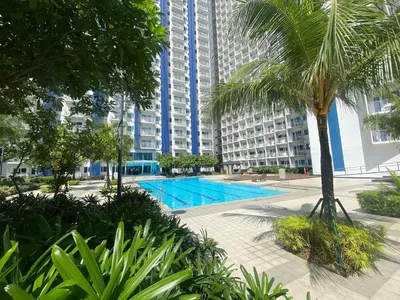 a swimming pool with palm trees and buildings at Will’s Place at Jazz Makati in Manila