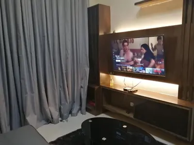 a living room with a tv and a curtain at H&M One Palmtree Villas in Manila