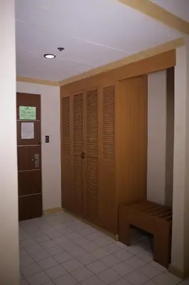 a room with wooden closet and a bench in it at Hotel Soriente in Manila