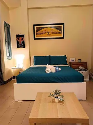 a bedroom with a bed and a wooden table at The Palm Tree Condotel Manila Airport in Manila