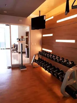 a gym with a wall filled with lots of dumbbells at The Palm Tree Condotel Manila Airport in Manila