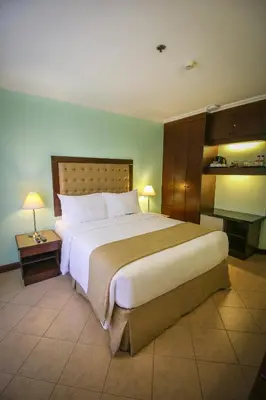 a large bed in a hotel room with two lamps at Royal Bellagio Hotel in Manila