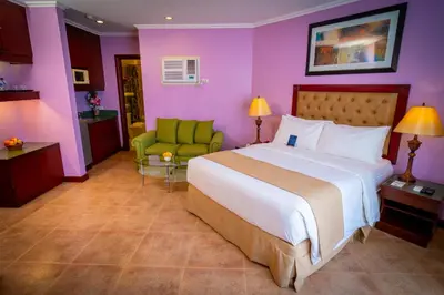 a bedroom with a large bed and a green chair at Royal Bellagio Hotel in Manila