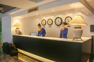 two people standing at a counter in a hotel with clocks at Royal Bellagio Hotel in Manila