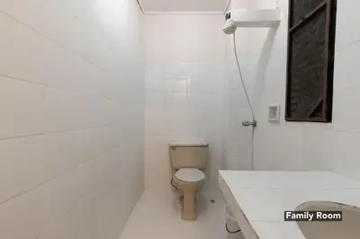 a white bathroom with a toilet and a sink at Victoria Mansions in Manila