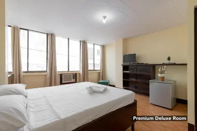 a bedroom with a large white bed and windows at Victoria Mansions in Manila
