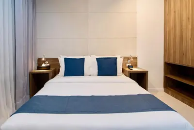 a bedroom with a large bed with blue pillows at The Sphere Serviced Residences Managed by HII in Manila