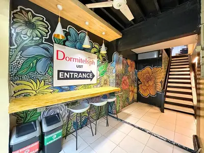 a sign on the wall of a restaurant with a counter and stools at Dormitelsph UST in Manila