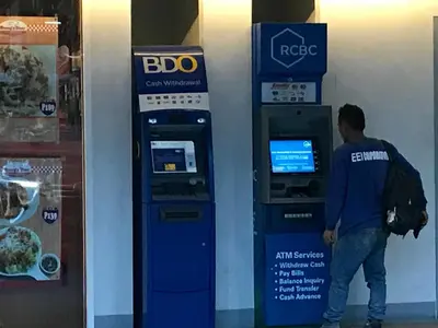 a man is standing next to an atm machine at Best Value Q Condo1439 in Manila