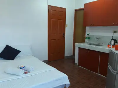a small kitchen with a bed and a sink at EKONUMI ROOMS at Moonwalk Paranaque in Manila