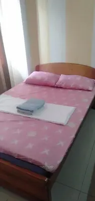 a pink bed with a laptop on top of it at EKONUMI ROOMS at Moonwalk Paranaque in Manila