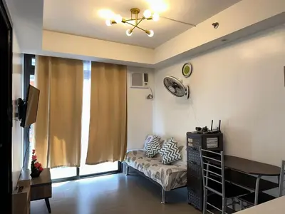 a living room with a couch and a window at A Home with a view, 1 Bdrm with balcony and Netflix Access in Manila