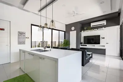 a kitchen with a white counter and a living room at Addie's Place Soldiers Hills Village Muntinlupa in Manila