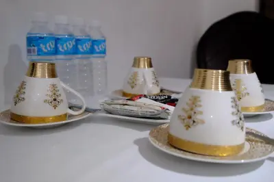 a table with three tea cups and plates with water bottles at Bing's Place in Manila
