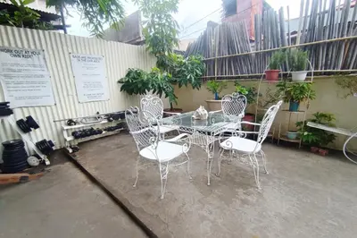 a glass table and chairs sitting on a patio at Bed and Brewhouse Sucat in Manila