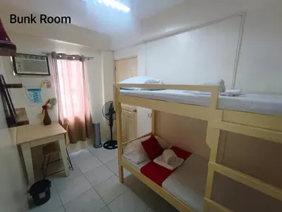 a dorm room with two bunk beds and a desk at Bed and Brewhouse Sucat in Manila