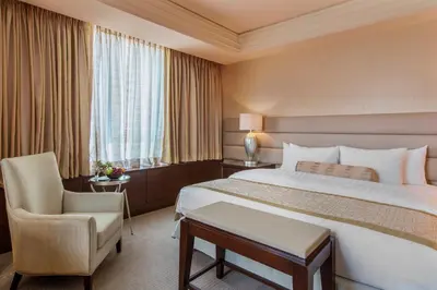 a hotel room with a large bed and a chair at Quest Plus Filinvest City Manila in Manila