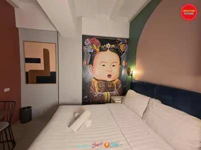 a bed in a room with a painting on the wall at Citizen Hotel in Manila