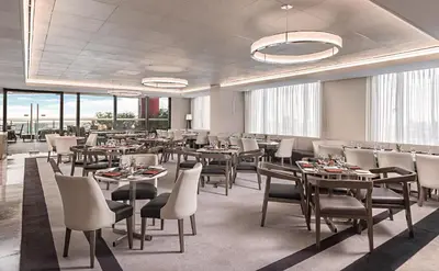 a dining room with tables and chairs and windows at Seda Residences Makati in Manila