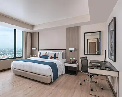 a hotel room with a bed and a desk and a computer at Seda Residences Makati in Manila