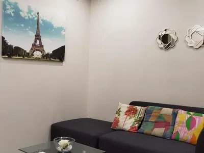 a living room with a couch and a picture of the eiffel tower at Jen's Paranaque City Apartment in Manila