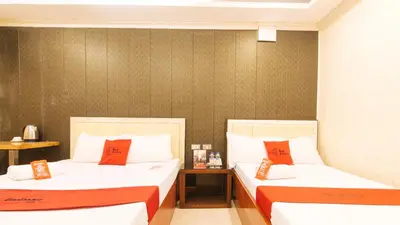 two beds in a hotel room with red pillows at RedDoorz Plus at Winter Benitez in Manila