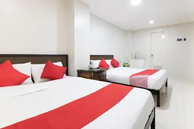 two beds in a hotel room with red pillows at OYO 152 Sangco Condotel in Manila