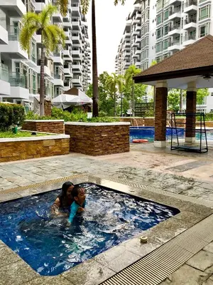 a young child playing in a swimming pool at Ameer Condotel @ Parkside Villa in Manila