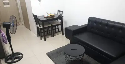 a living room with a black couch and a table at 1 Bedroom Apartment @SMDC Shore Residences, Mall of Asia in Manila