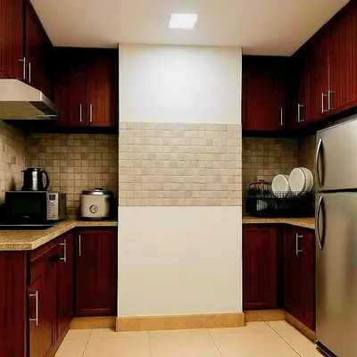 a kitchen with wooden cabinets and a white wall at JMM Grand Suites in Manila