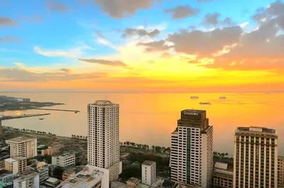 a view of a city with a sunset over the water at JMM Grand Suites in Manila