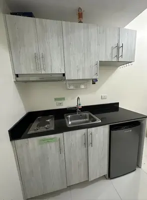 a kitchen with gray cabinets and a sink at Green Residences Stays by PBYY in Manila